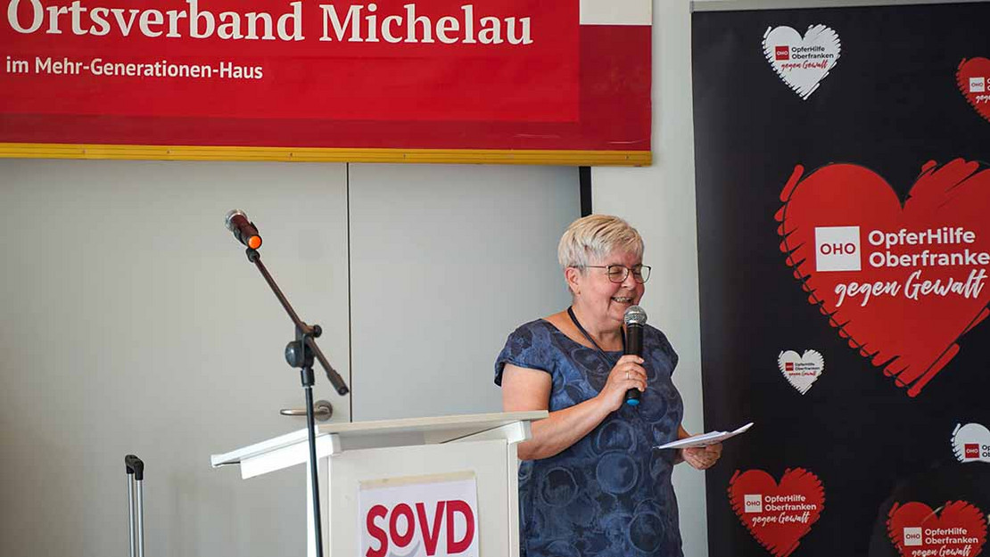 Eine Frau spricht in ein Mikrofon. Hinter ihr ein Banner mit der Aufschrift "Ortsverband Michelau"