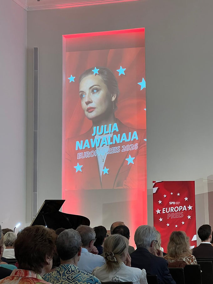 Plakat auf Bühne und Publikum von hinten.